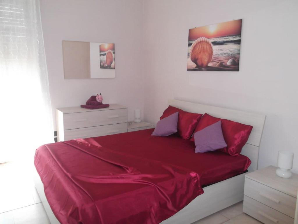 1 dormitorio con 1 cama con edredón rojo en Attico trilocale con solarium a Borghetto Santo Spirito, en Borghetto Santo Spirito