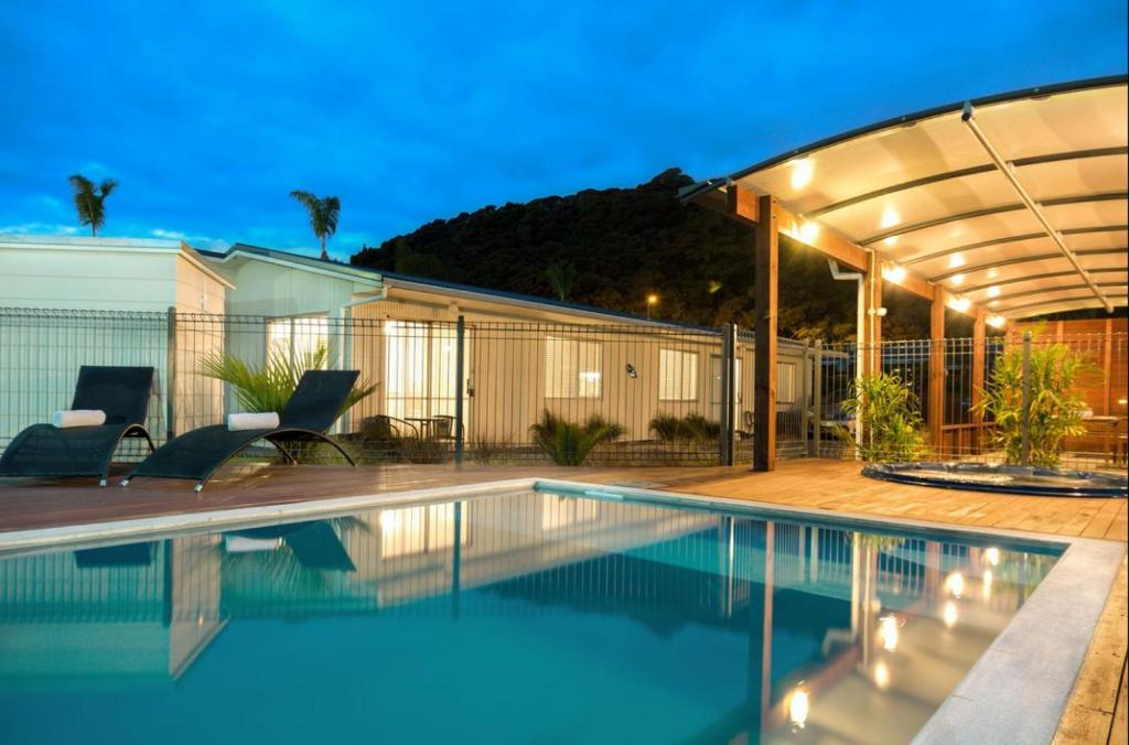 uma piscina com uma pérgula ao lado de uma casa em Averill Court Motel em Paihia