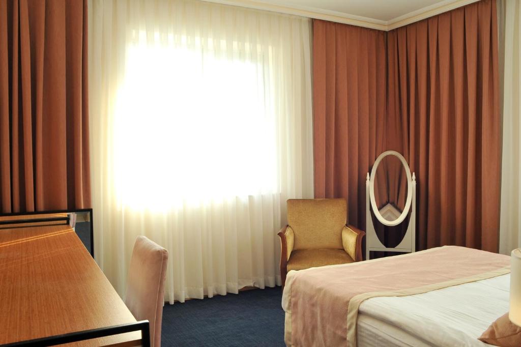 a hotel room with a bed and a chair and a mirror at Lion City Hotel Ankara in Ankara