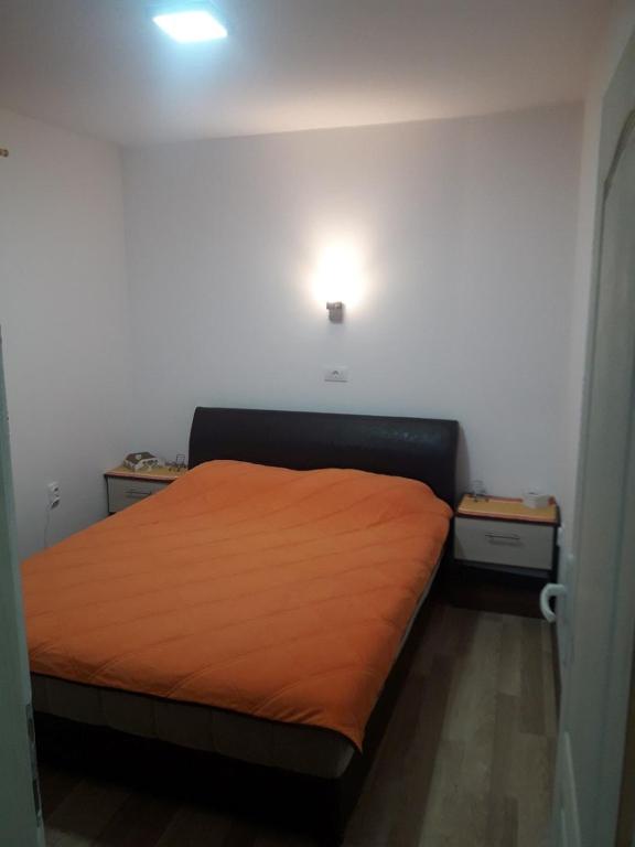 een slaapkamer met een bed met een oranje deken bij Apartmani Nikola u vili Semeteš in Kopaonik