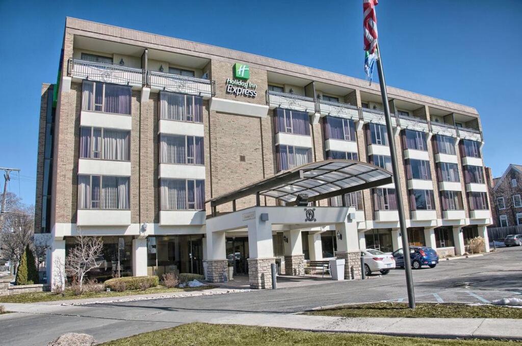 un gran edificio con una bandera delante de él en Holiday Inn Express Detroit-Birmingham, an IHG Hotel, en Birmingham