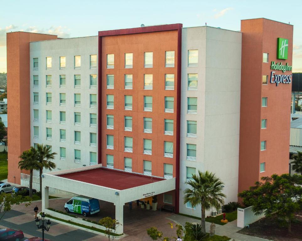 un edificio de hotel con un coche aparcado delante de él en Holiday Inn Express Guadalajara Aeropuerto, an IHG Hotel, en Guadalajara