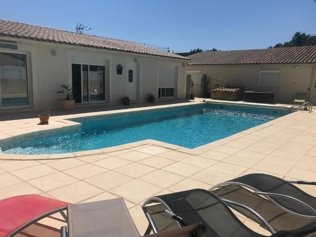 a swimming pool with chairs and a house at LES CLÉMATITES in Donzère