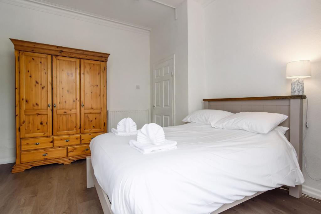 1 dormitorio con 1 cama blanca grande y armario de madera en Handpost Lodge, en Newport