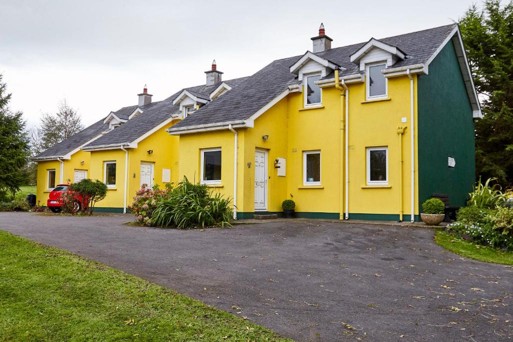 a yellow and green house with a driveway at Mount Brandon Cottages Graiguenamanagh in Graiguenamanagh