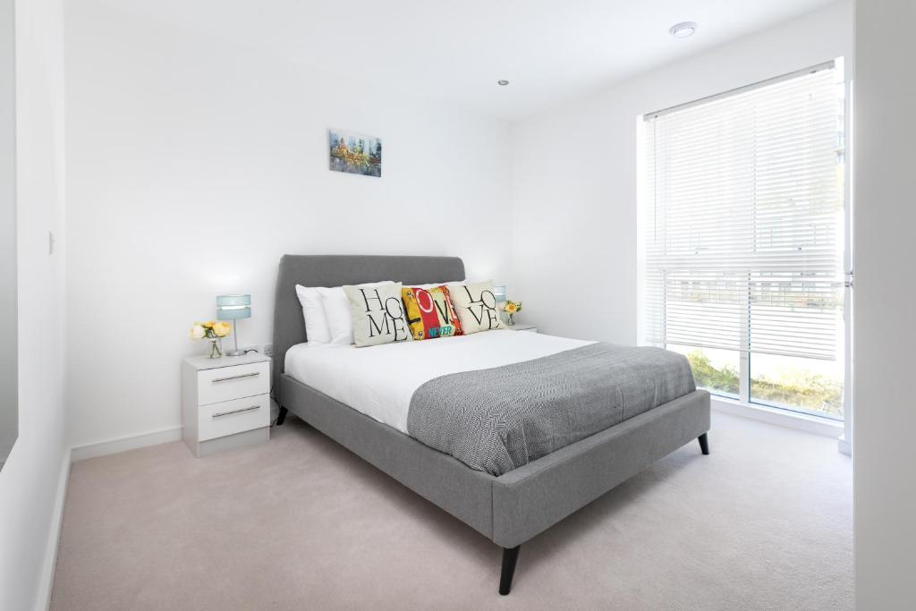 a white bedroom with a bed and a window at Skyvillion - Olympic View London Stratford Apartment in London