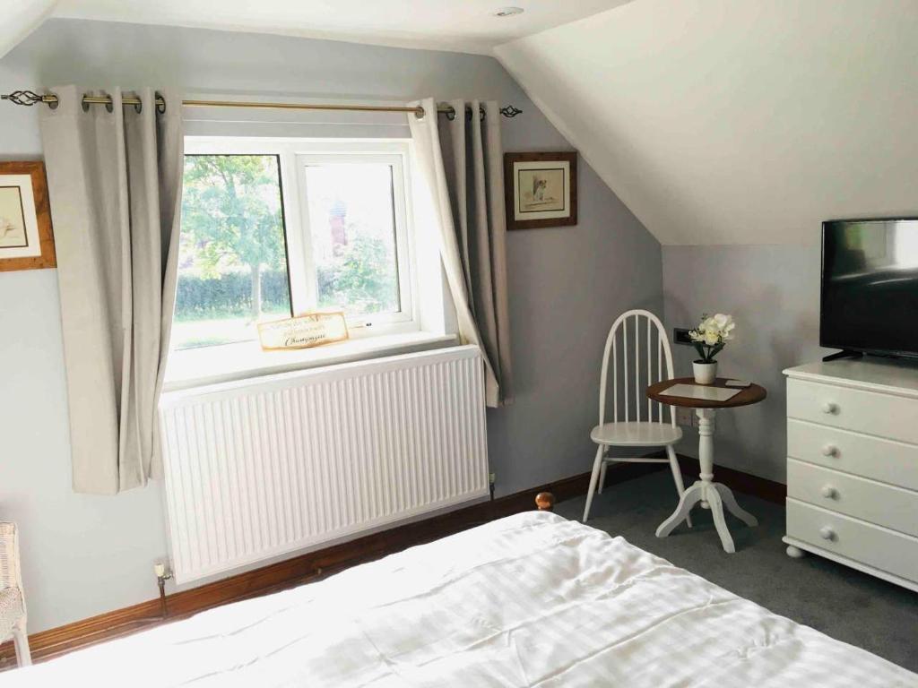um quarto com uma cama, uma janela e uma cadeira em The Loft em Congleton