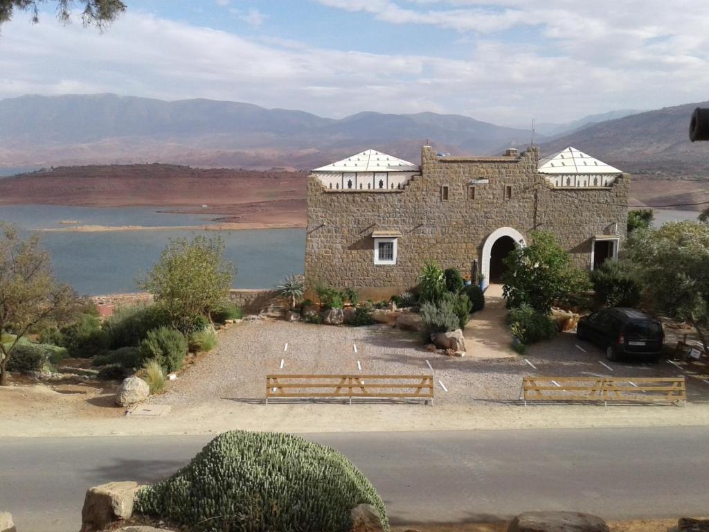 a stone building with a gate and a body of water at Tigmi Dar Samy in Bine el Ouidane