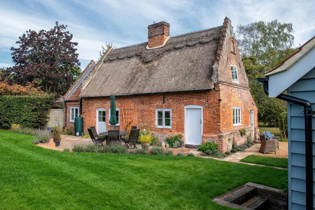 an old brick house with a grass yard at Thatch Cottage - luxury Norfolk Hideaway in Norwich