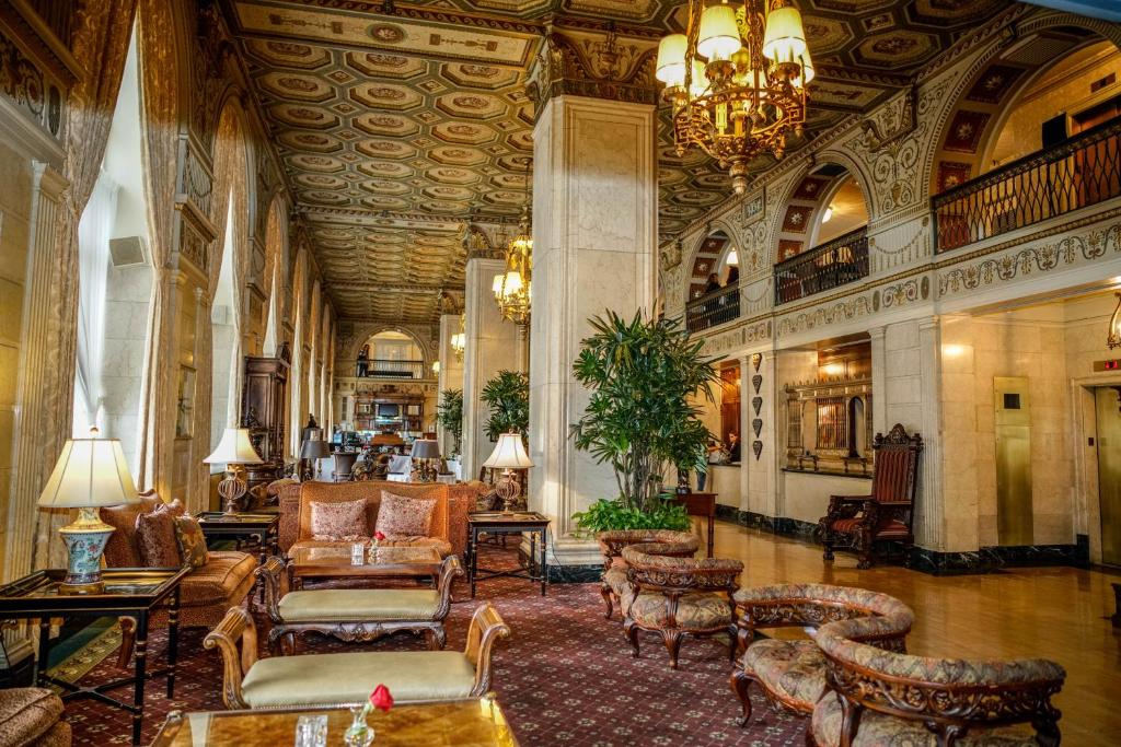 a large lobby with chairs and tables and a chandelier at The Brown Hotel in Louisville