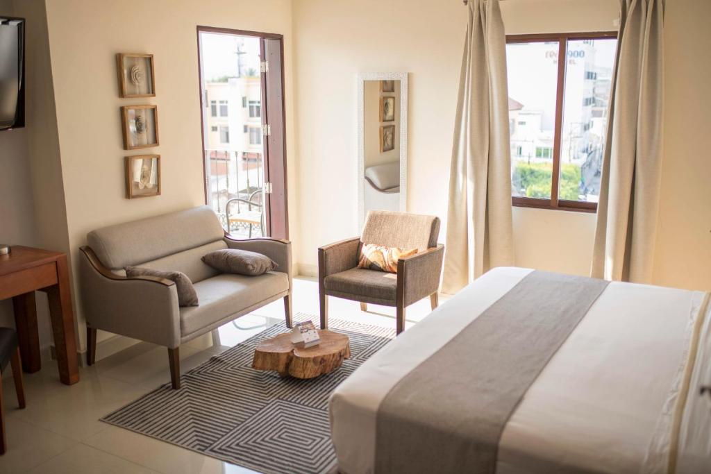 a hotel room with a bed and two chairs at Gran Plaza Hotel Centro Histórico in Iguala de la Independencia