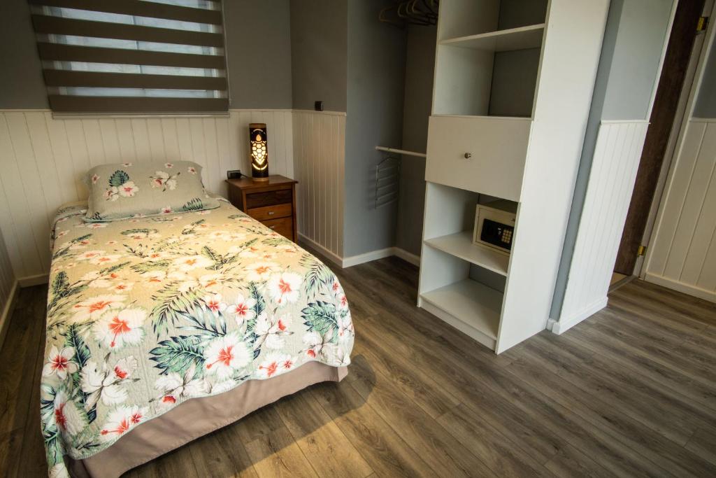 a bedroom with a bed with a floral bedspread at Inaki Uhi Hotel in Hanga Roa