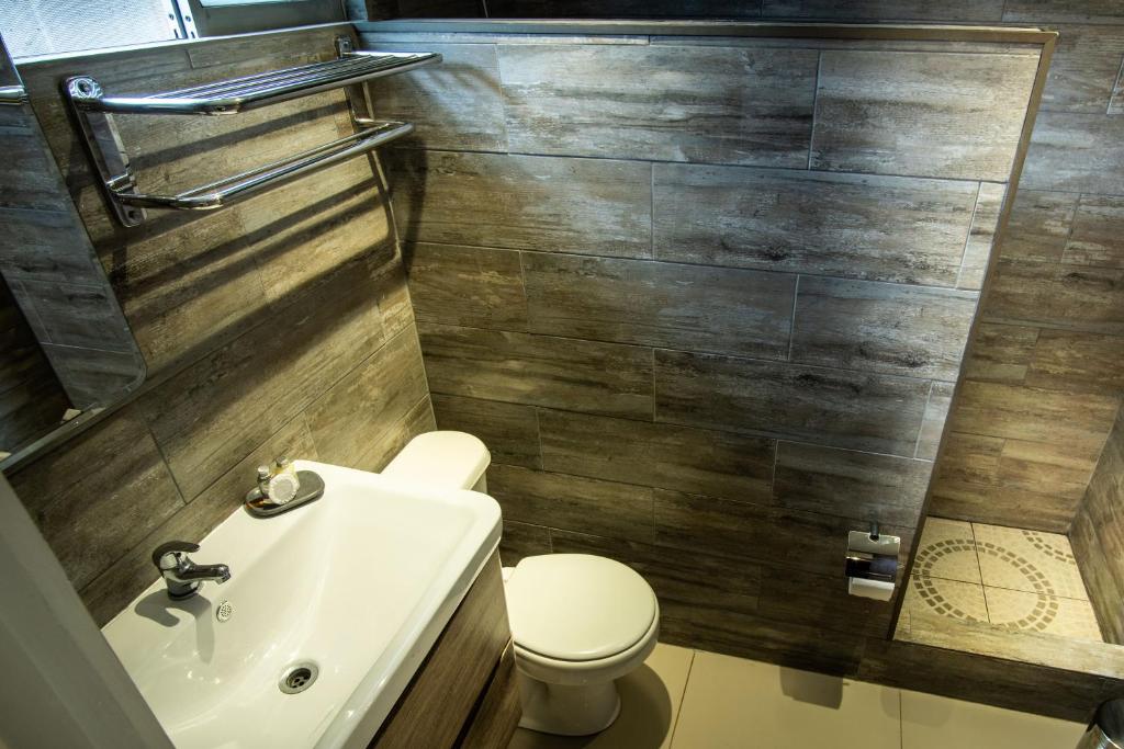 a bathroom with a white toilet and a sink at Inaki Uhi Hotel in Hanga Roa