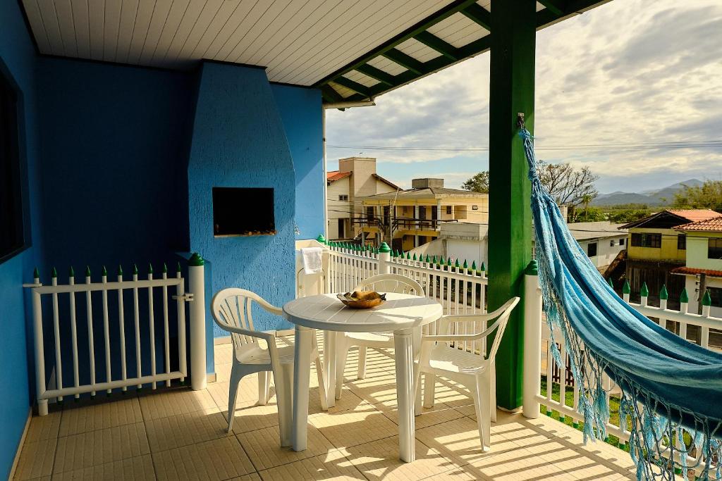 a porch with a white table and chairs on a balcony at Resid.l Canto do Encanto in Garopaba