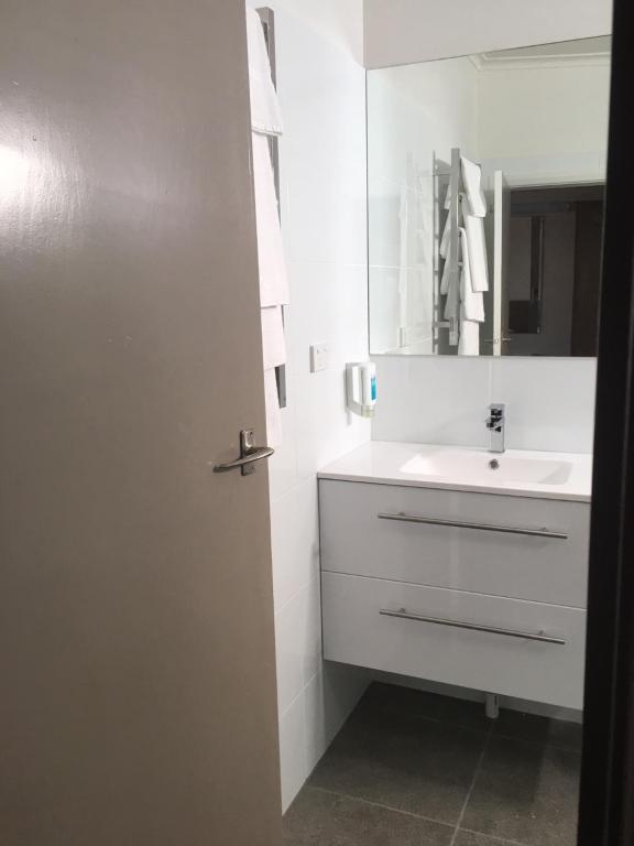 a white bathroom with a sink and a mirror at Argosy Motor Inn in Devonport