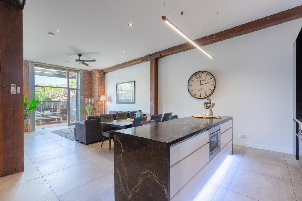 uma cozinha e sala de estar com um relógio na parede em Luxury 3 brm 2 bath Woolstore apt with Courtyard em Brisbane