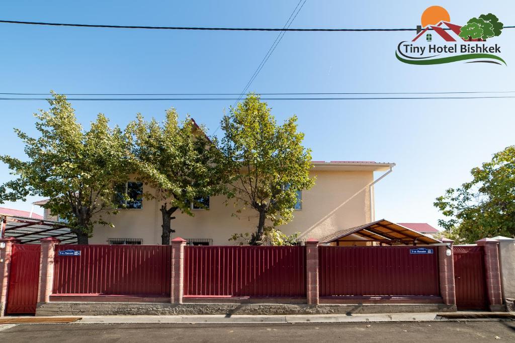ein roter Zaun vor einem Haus in der Unterkunft Tiny Hotel Bishkek in Bischkek