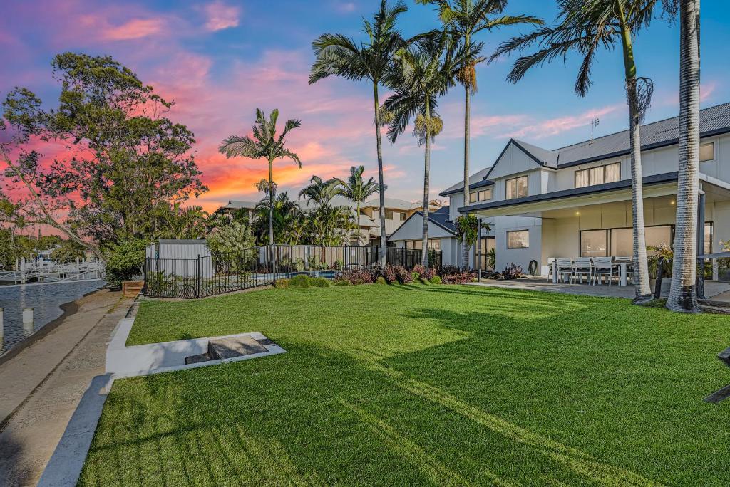 a backyard with palm trees and a house at CANAL HOME NEAR MOOLOOLABA - Kooringal in Buddina