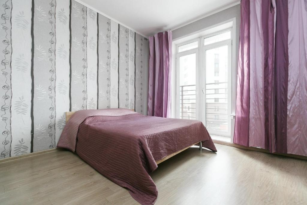 ノヴォシビルスクにあるApartments Freedom on Shamshinykhのベッドルーム1室(ベッド1台付)、ピンクのカーテン付きの窓が備わります。