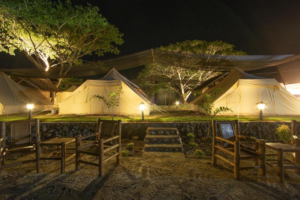 a group of tents with tables and chairs at night at The Acacia Glamping Park in Carmen
