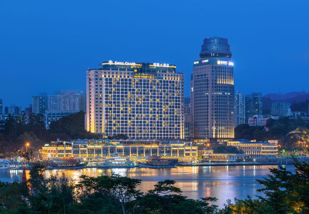 a city with tall buildings and a river at night at Swiss Grand Xiamen-Harbour View in Xiamen