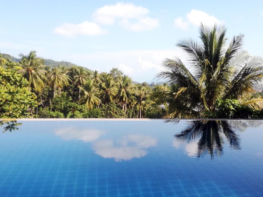 een blauw zwembad met palmbomen op de achtergrond bij Koh Samui Palm View Villa in Chaweng Beach