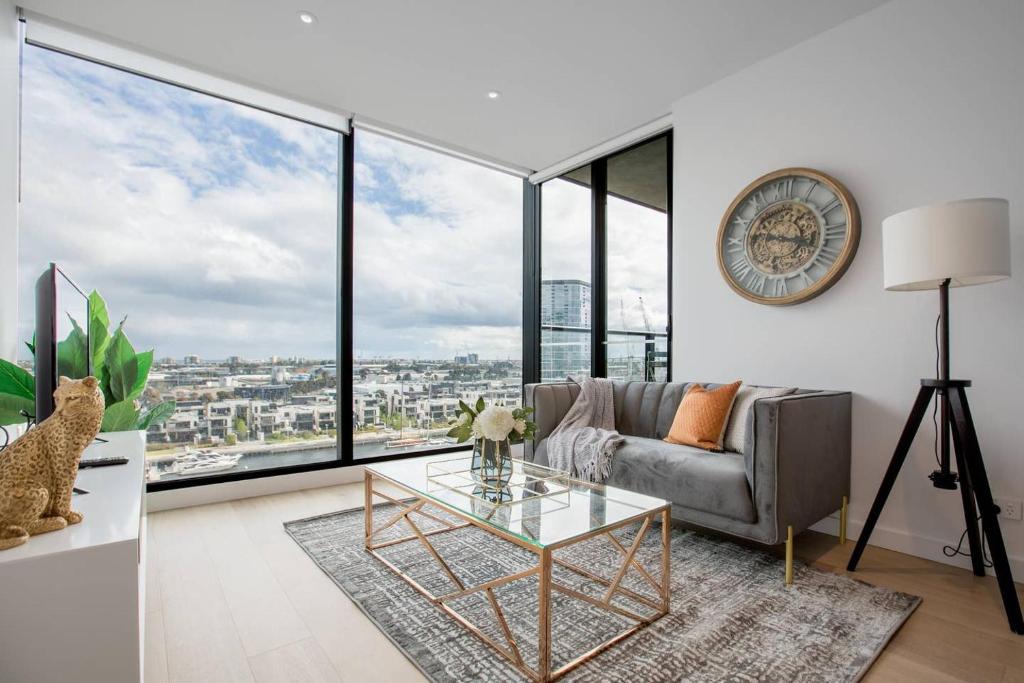 a living room with a couch and a clock on the wall at Delightful 2BR Riverview@Docklands in Melbourne