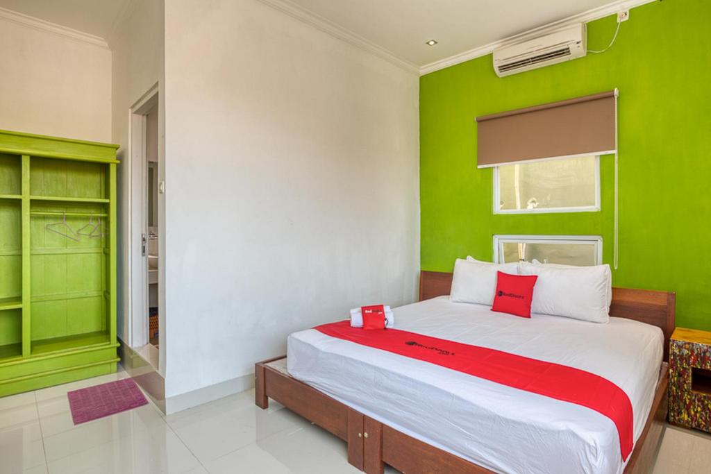 a bedroom with green and white walls and a bed at RedDoorz near Bali Zoo Ubud in Sukawati