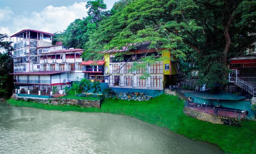 a group of buildings on the side of a river at Hotel Gangaaddara in Kandy