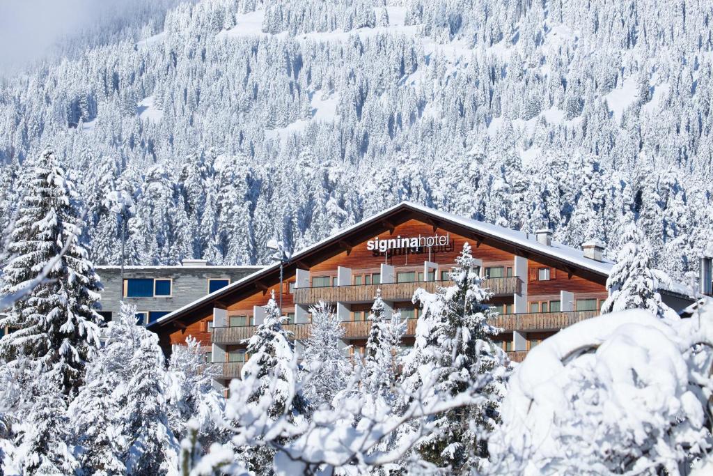 een met sneeuw bedekt gebouw voor een berg bij signinahotel in Laax