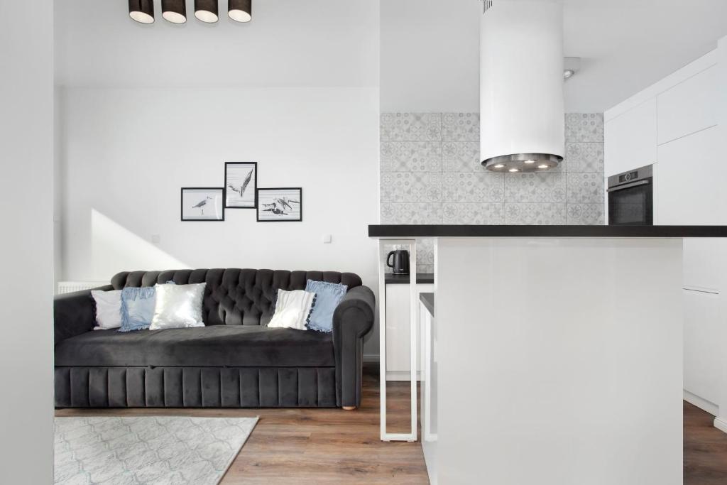 a living room with a black couch and white walls at Elite Apartments Luna Spa&Welness in Gdańsk