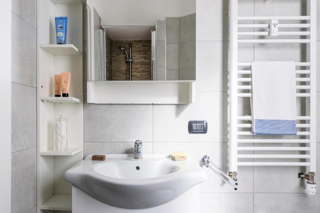 biała łazienka z umywalką i lustrem w obiekcie Pascoli Master Guest apartment w mieście Sesto San Giovanni