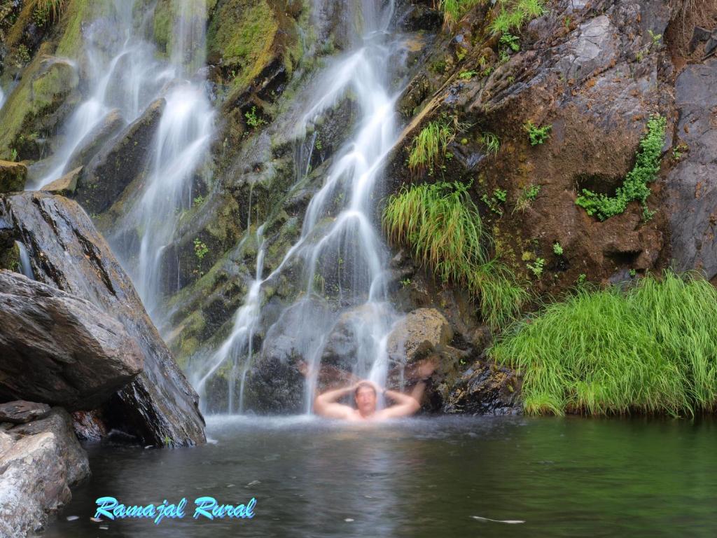 a woman is swimming in a waterfall at Ramajal Rural in Horcajo