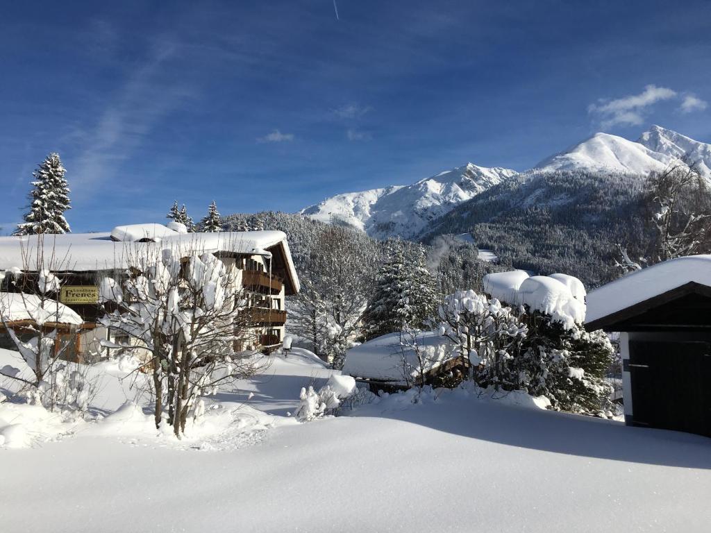 una casa cubierta de nieve con montañas en el fondo en Landhaus Frenes Apartments, en Seefeld in Tirol