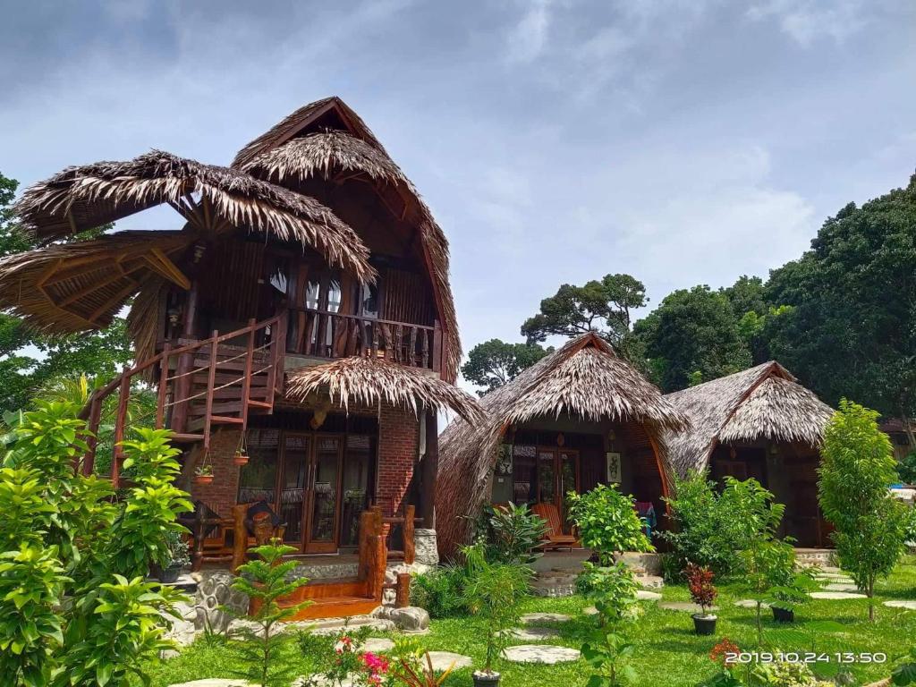 un groupe de cabanes à toiture en herbe dans l'établissement Green Travelodge Bukit Lawang, à Bukit Lawang