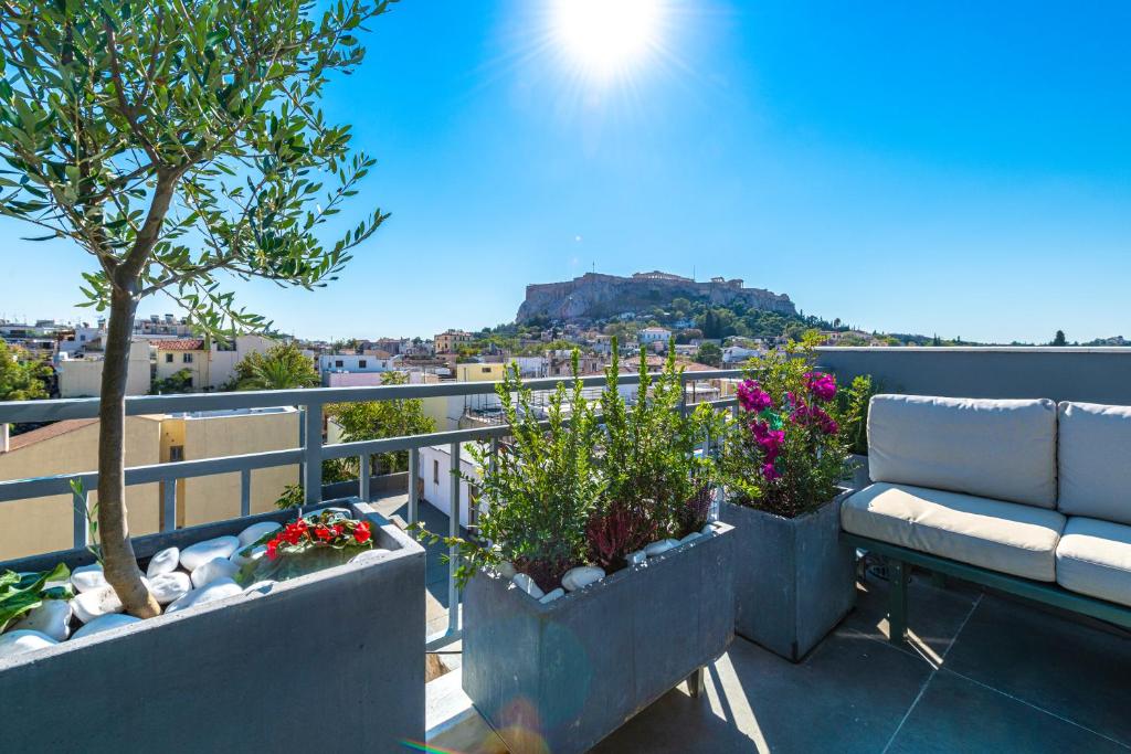 eine Terrasse mit Sofa und Blumen auf dem Balkon in der Unterkunft Hidesign Athens Acropolis Panorama Suite in Athen