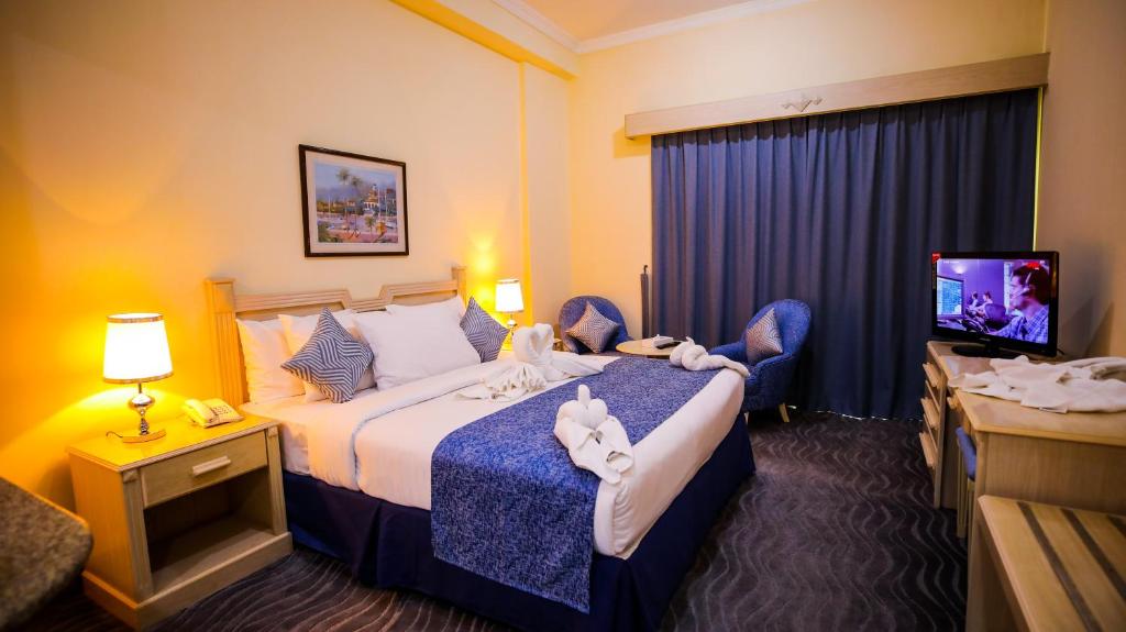 Green House Hotel Suites & Apartment في دبي: غرفة فندق بسرير وتلفزيون