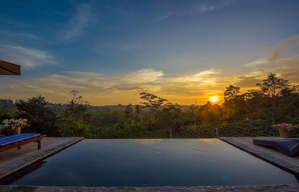 a pool with a bench and the sunset in the background at Kahanda Kanda in Koggala