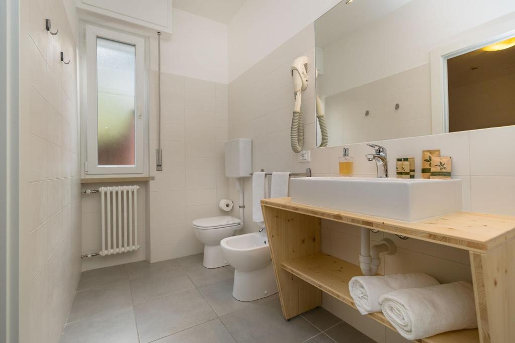 uma casa de banho branca com um lavatório e um WC em Hotel Villa Carmen em Malcesine