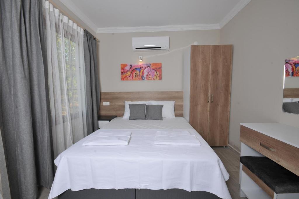 een slaapkamer met een groot wit bed en een raam bij SELERDOĞA EVLERİ in Mugla