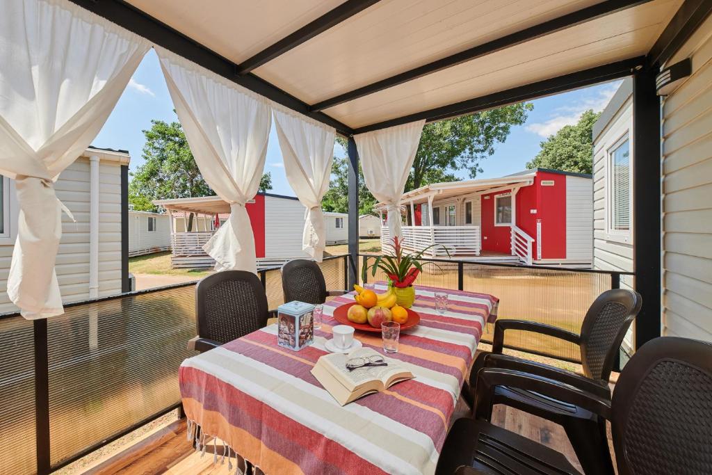 a table with a book and fruit on a balcony at Camping Adria Mobile Home Park Umag in Umag