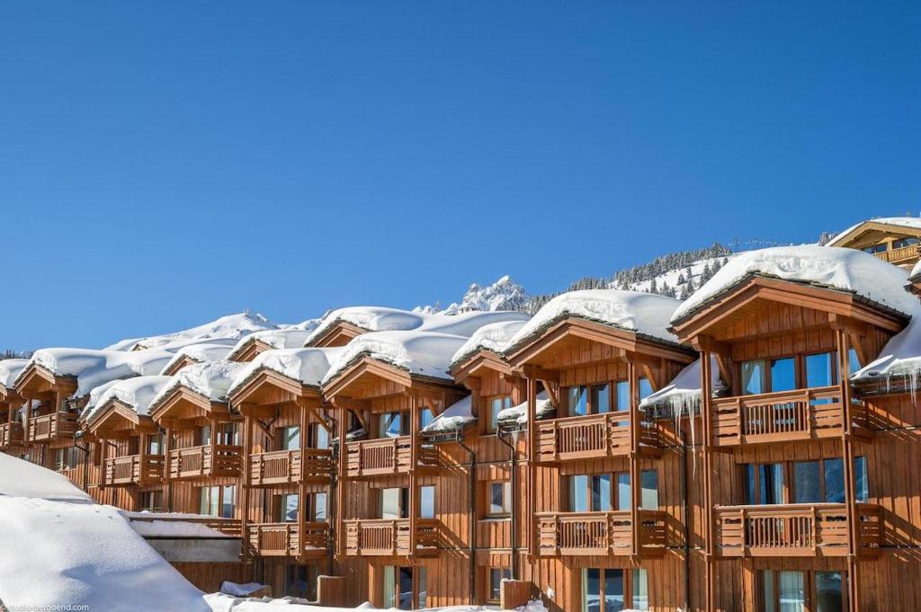 um edifício coberto de neve com telhados cobertos de neve em Résidence Les Chalets du Forum - Courchevel 1850 em Courchevel