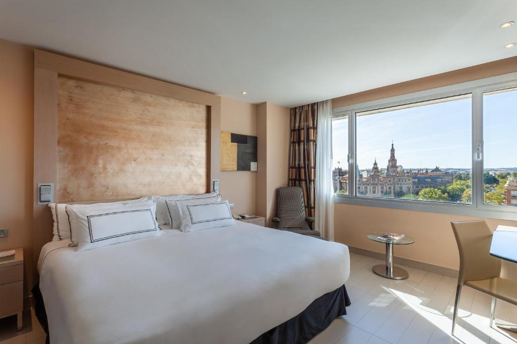 um quarto de hotel com uma cama grande e uma janela grande em Melia Sevilla em Sevilha