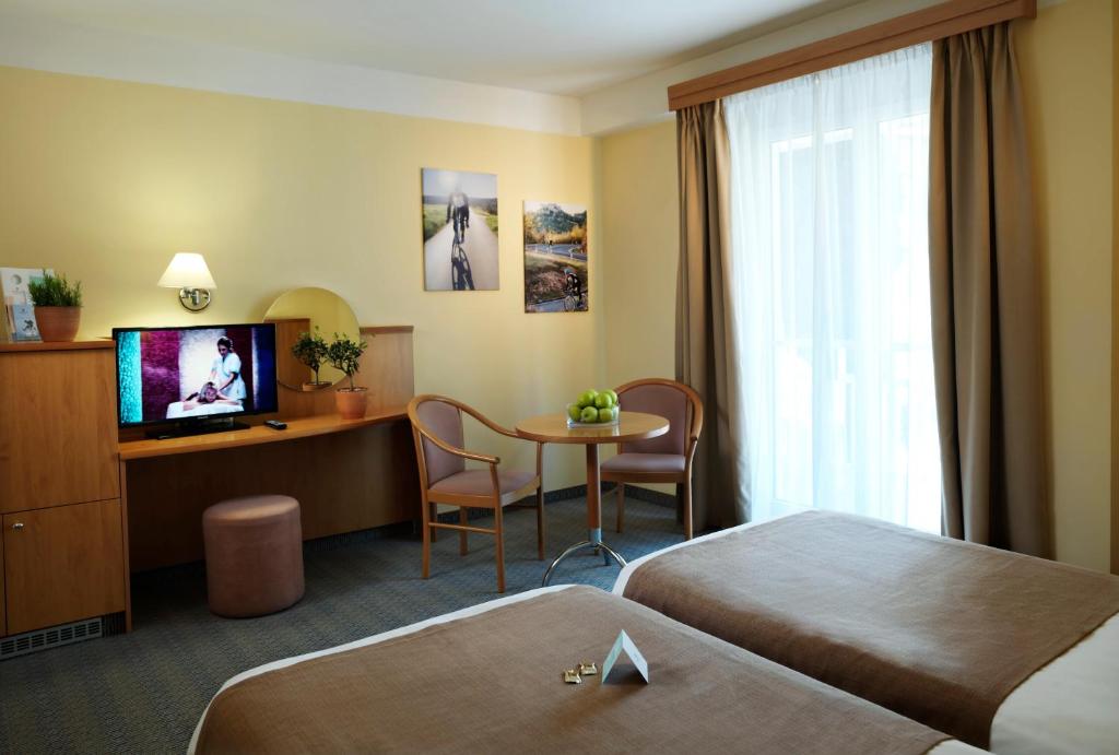 a hotel room with two beds and a table and a tv at Hotel Neptun - Terme & Wellness Lifeclass in Portorož