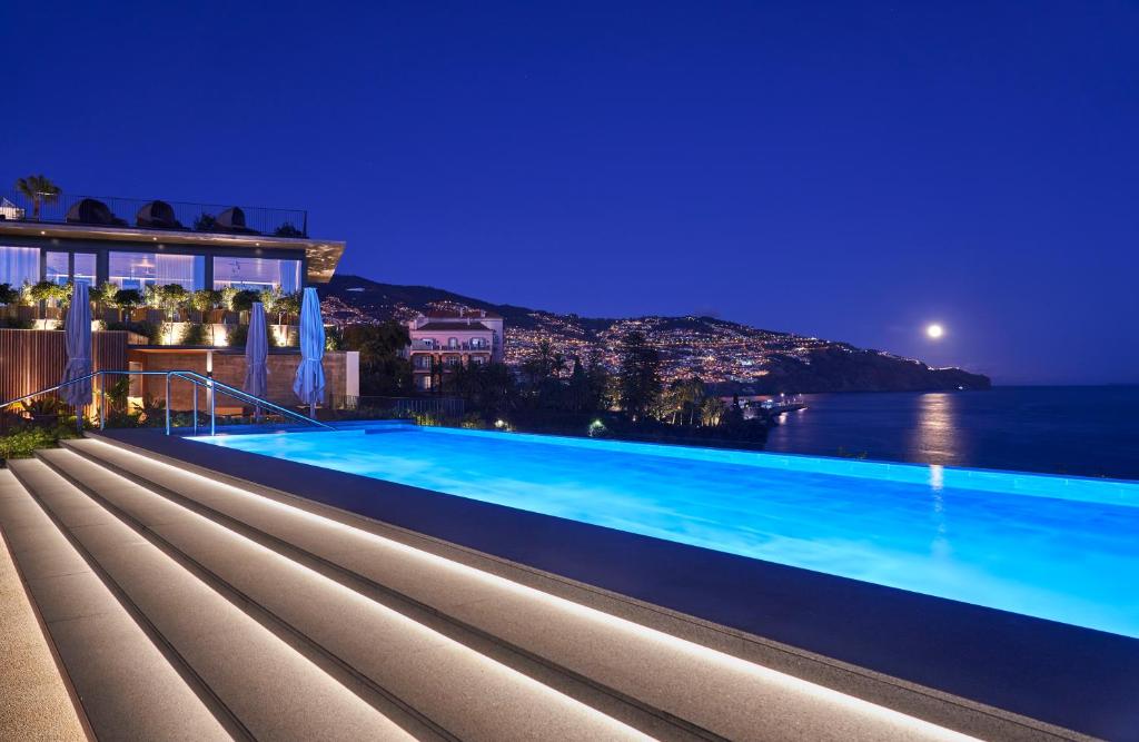 a view of a swimming pool at night at Les Suites at The Cliff Bay - PortoBay in Funchal