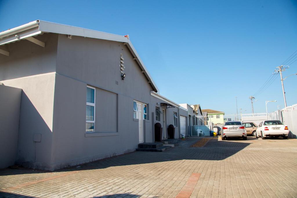 Cape Town的住宿－ANNEX LODGE & SPa，白色的建筑,有汽车停在停车场