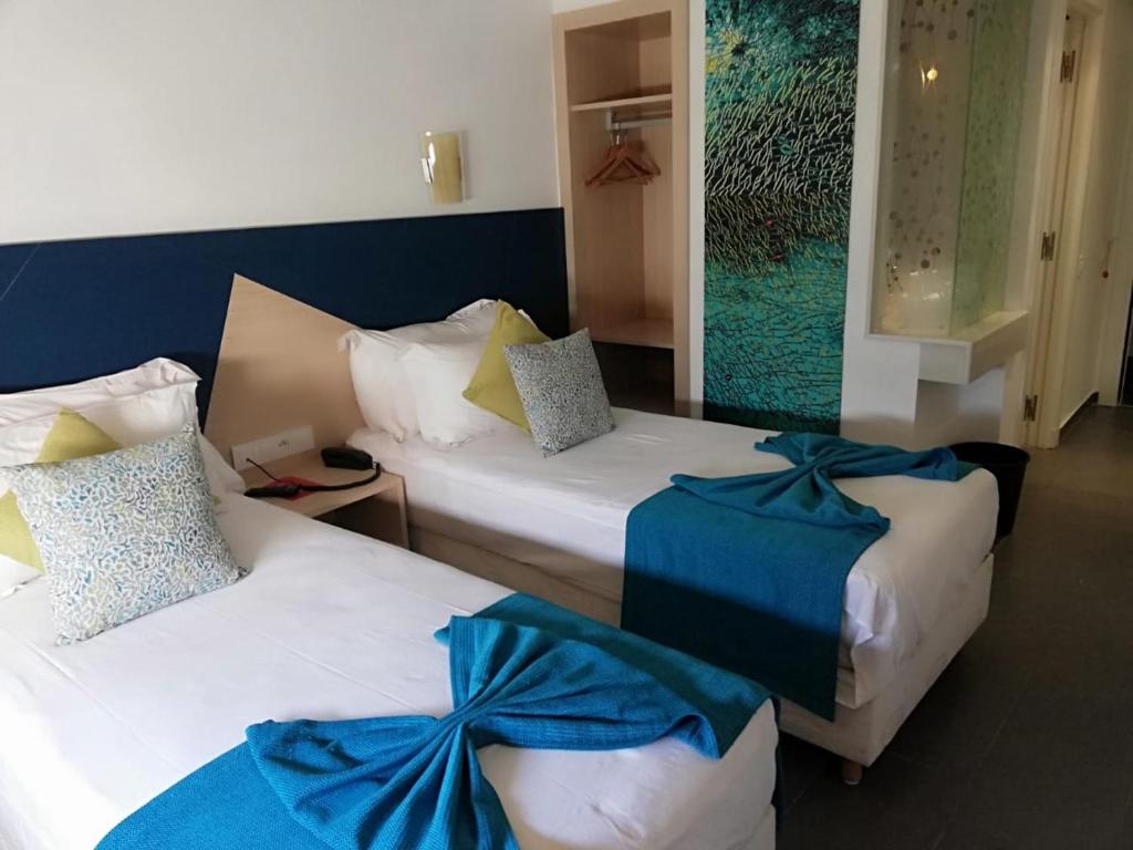 2 posti letto in camera d'albergo con fiocchi blu di Relax Hôtel Oujda a Oujda