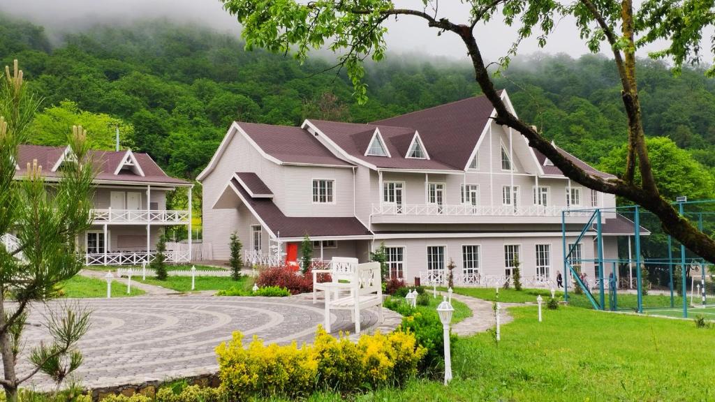 una gran casa blanca con un parque infantil delante de ella en Macara Village Resort, en Quba