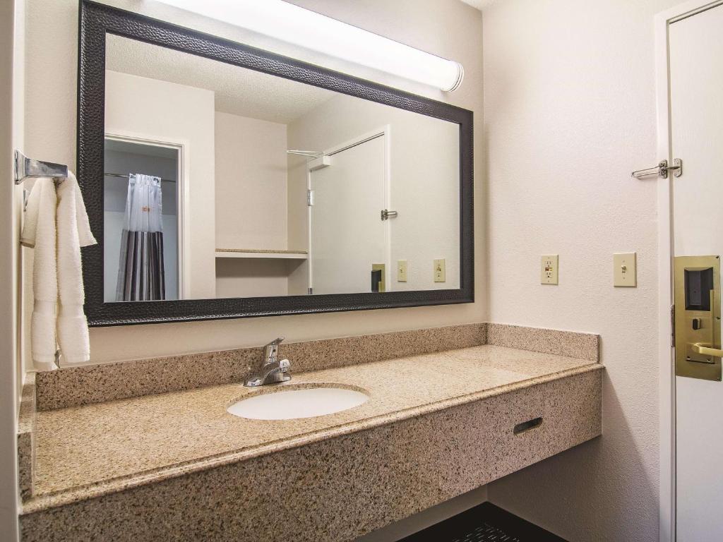 a bathroom with a sink and a large mirror at Wingate by Wyndham Brunswick GA I-95 in Brunswick