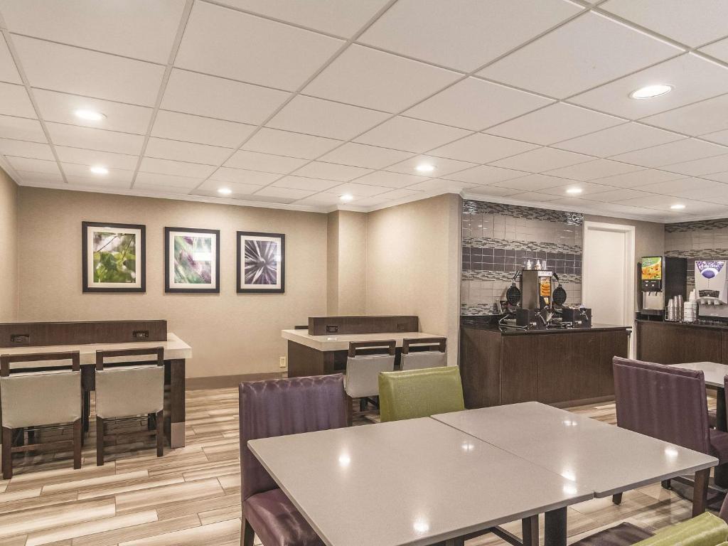 a waiting room with tables and chairs in a restaurant at Wingate by Wyndham Brunswick GA I-95 in Brunswick